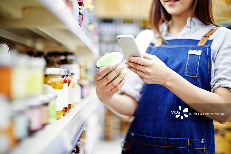 熟食店老板用智能手机扫描食品容器上的标签图片素材