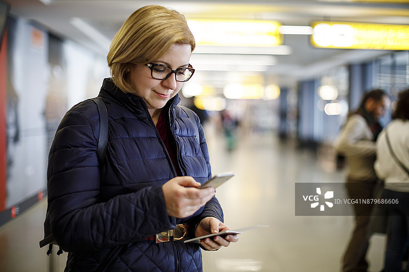 在机场航站楼使用手机的女乘客图片素材