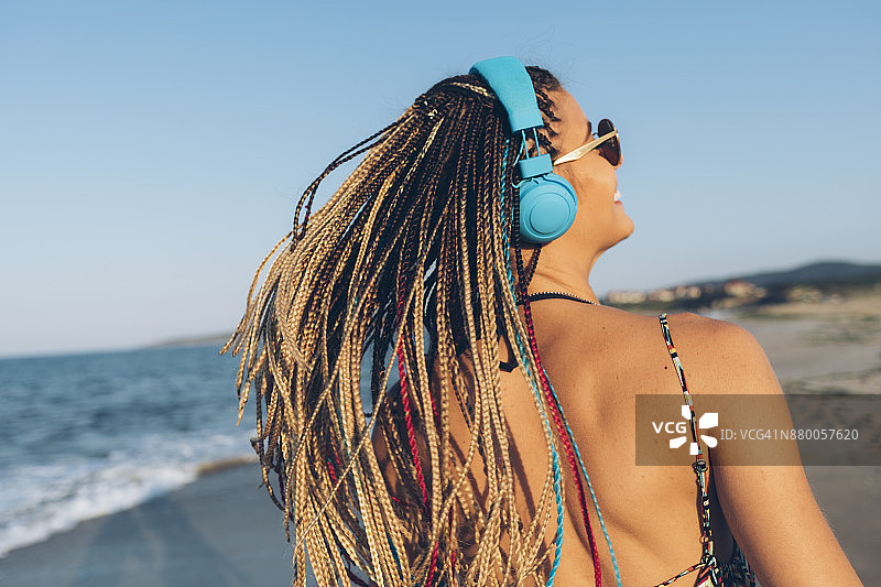 在海滩听音乐的快乐年轻女人图片素材