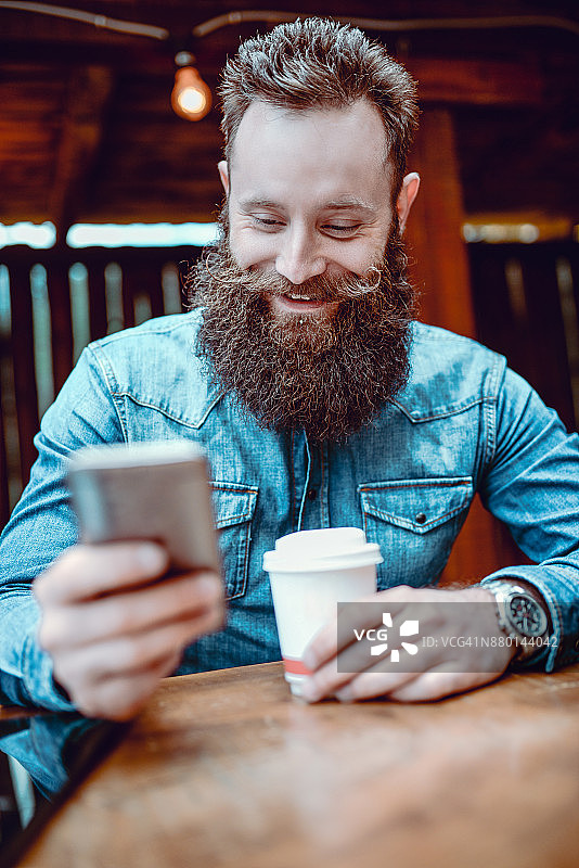 迷人的微笑潮人在发短信和喝咖啡图片素材