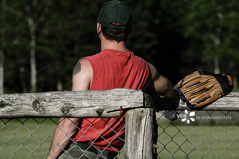 靠在铁丝网上的垒球运动员图片素材