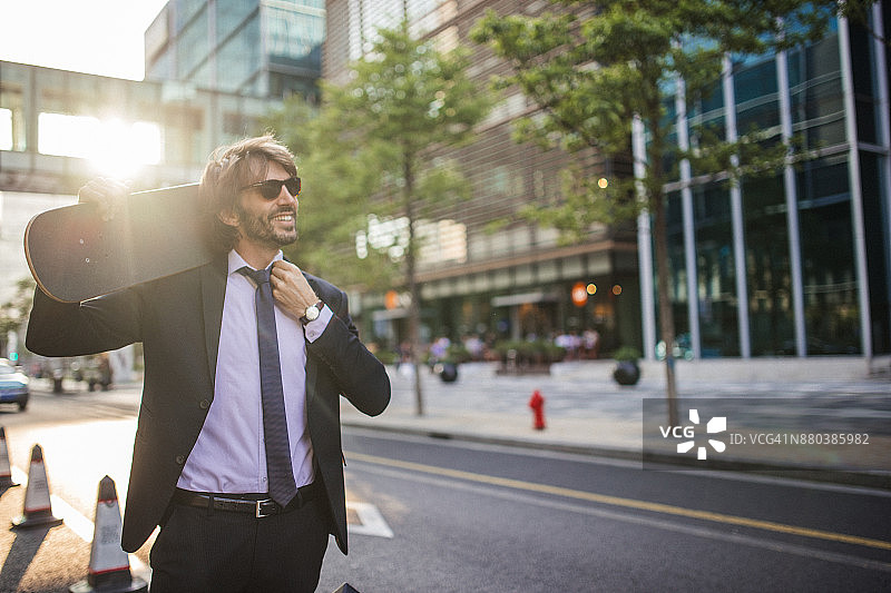 现代商人肩扛滑板图片素材