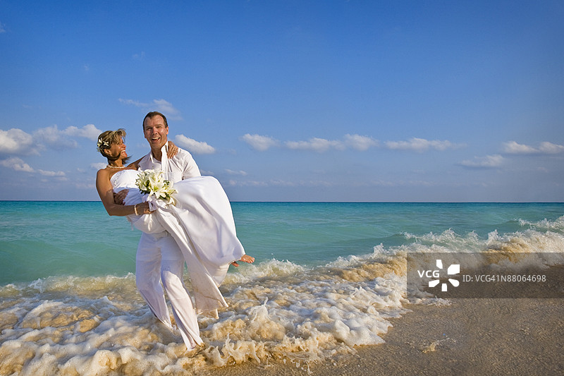 新郎在海滩上抱着新娘图片素材