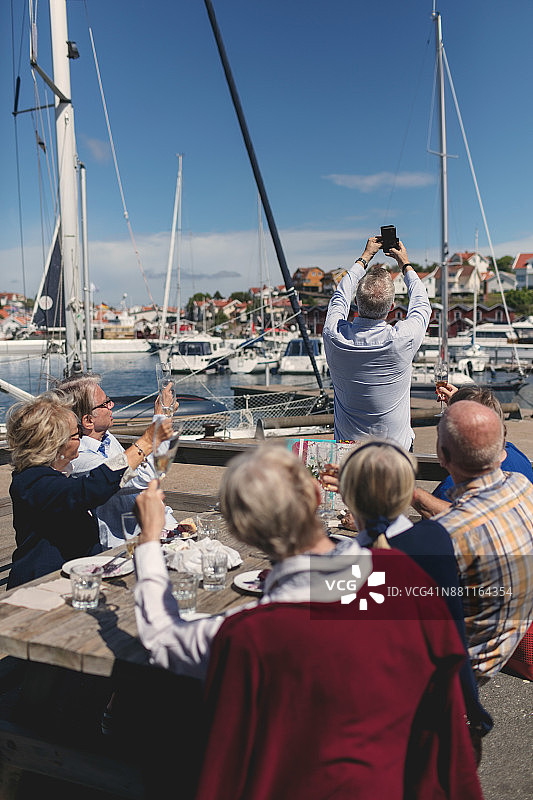 在餐厅露台上与朋友用手机自拍的老年男人图片素材