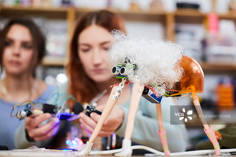 年轻女发明家在工作室制作机器人模型图片素材