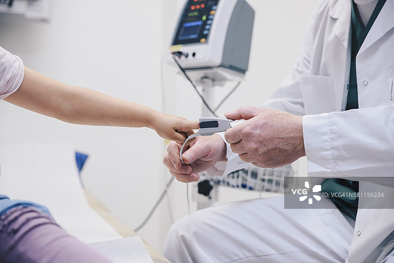 成熟医生在医院调整女孩手指上的脉搏血氧仪图片素材
