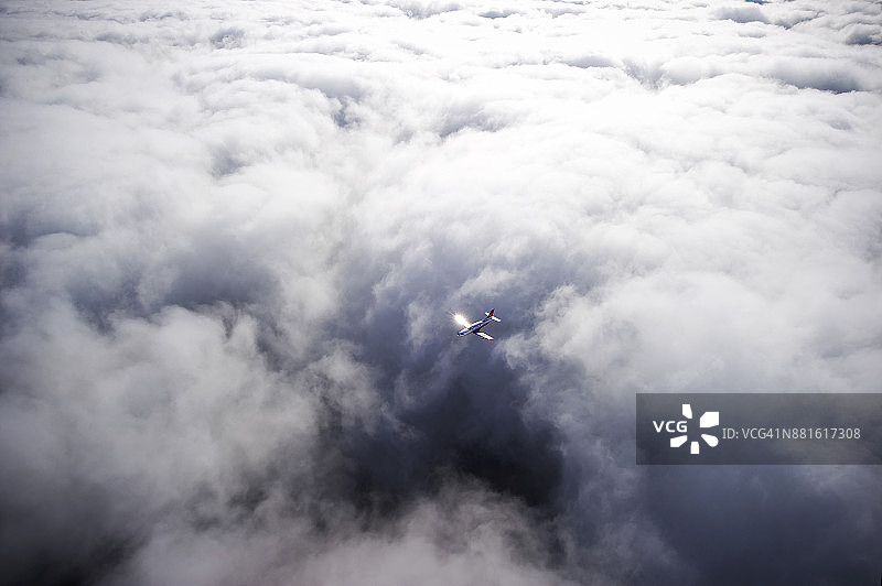 阳光下在云层上空飞行的私人飞机图片素材