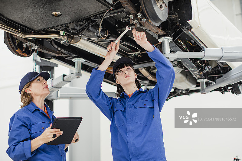正在修理汽车的实习女机械师图片素材