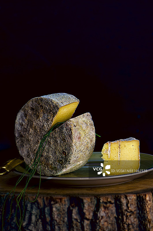 搭配韭菜的洛克福奶酪头，在木制横截面上供应，明暗对比照明，黑暗忧郁风格图片素材