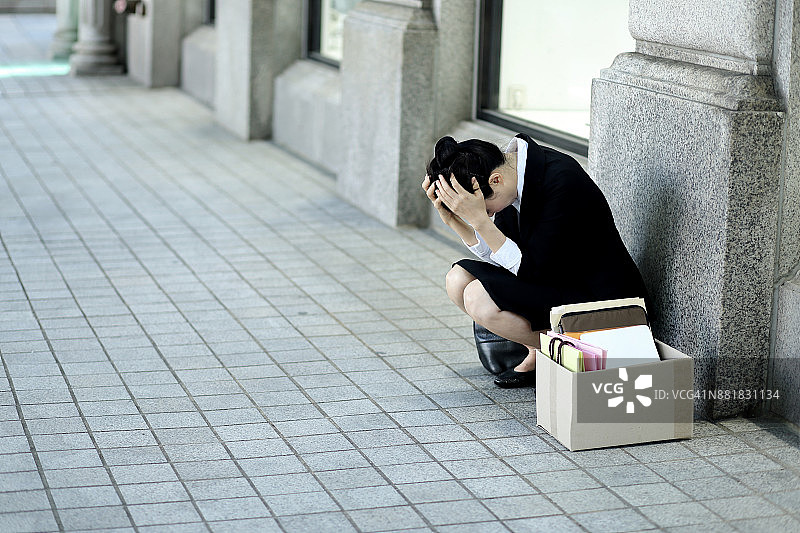 坐在户外，抱着包装盒的沮丧女商人图片素材