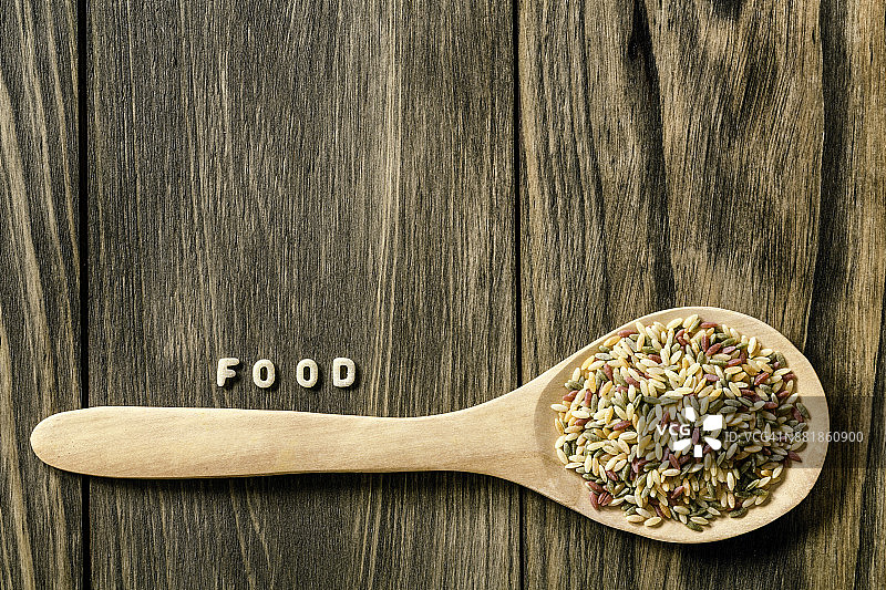 乡村木桌上的意大利面食食品标志，木板上有复制空间，木勺中有彩色奥佐面图片素材