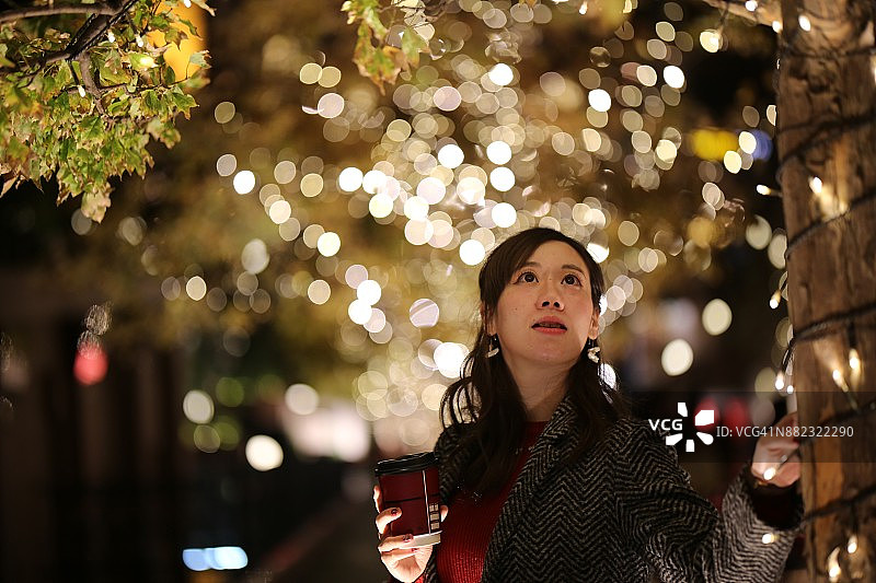 站在圣诞树旁的年轻女子图片素材