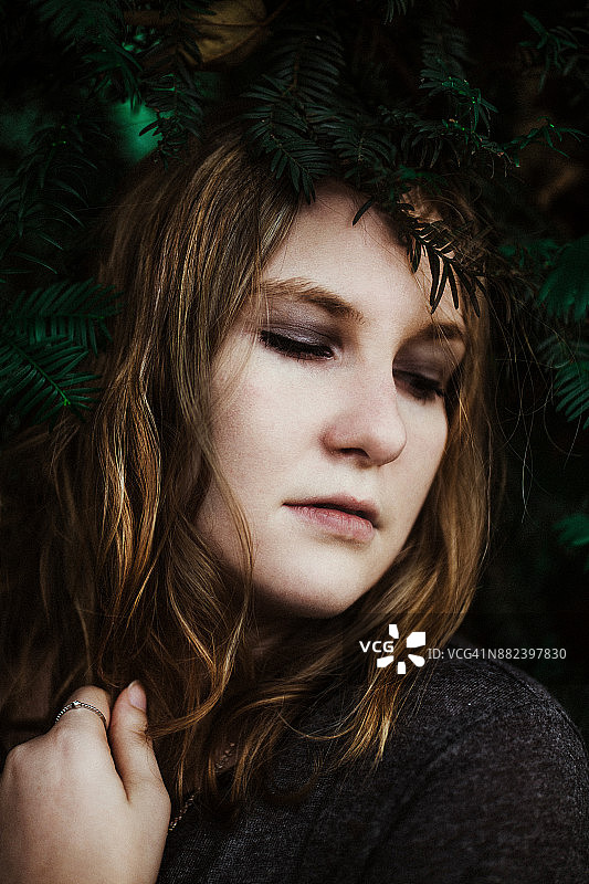 冷杉树枝中沉思的女子肖像图片素材