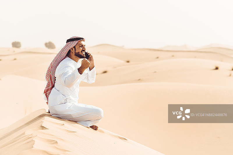 在沙漠里打电话的阿拉伯男子图片素材