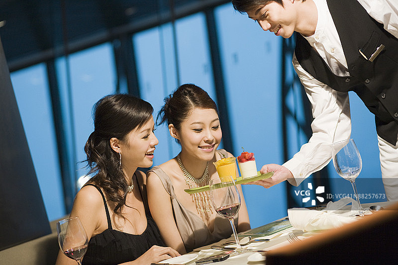 餐厅服务员为年轻女士提供甜点图片素材