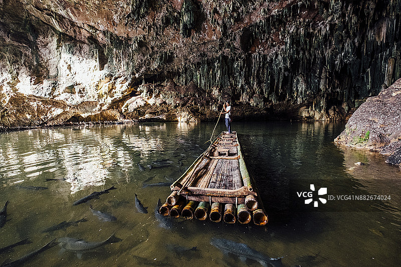 男子在洞穴中划着装满鱼的大木筏图片素材