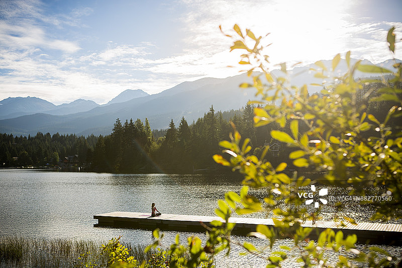 年轻女子在湖边码头上练习瑜伽图片素材
