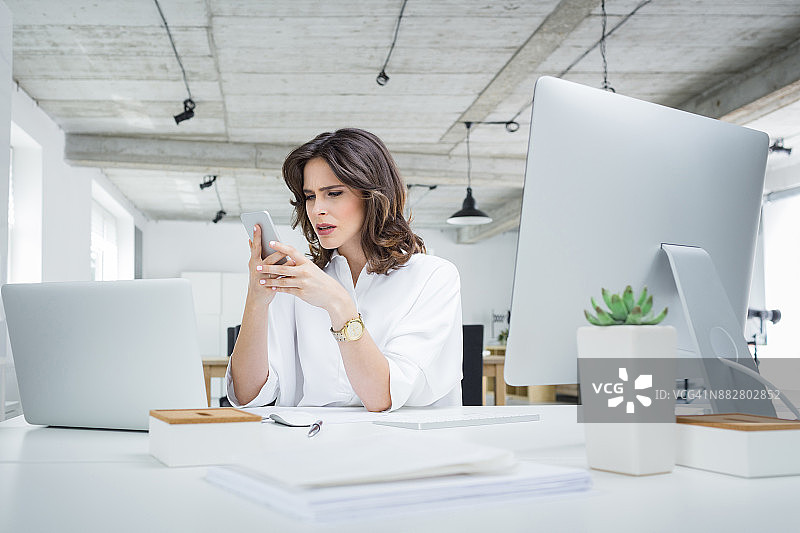 在办公室使用手机的焦虑女商人图片素材