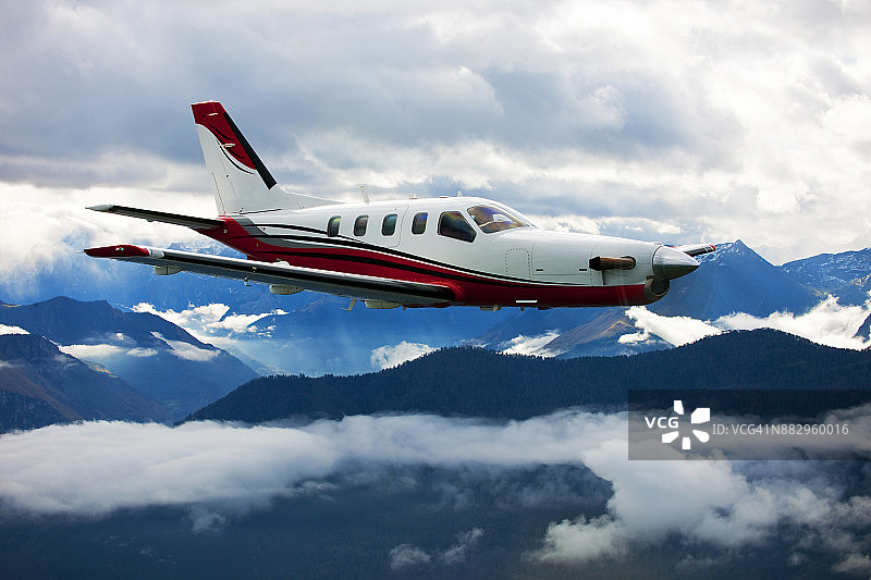 一架涡轮螺旋桨私人飞机飞越群山，天空壮丽图片素材