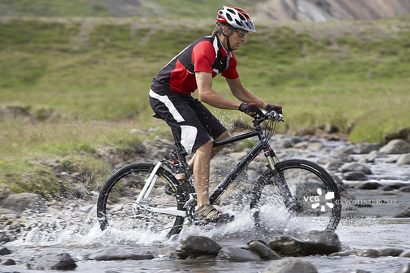 骑自行车穿过小溪的男人图片素材