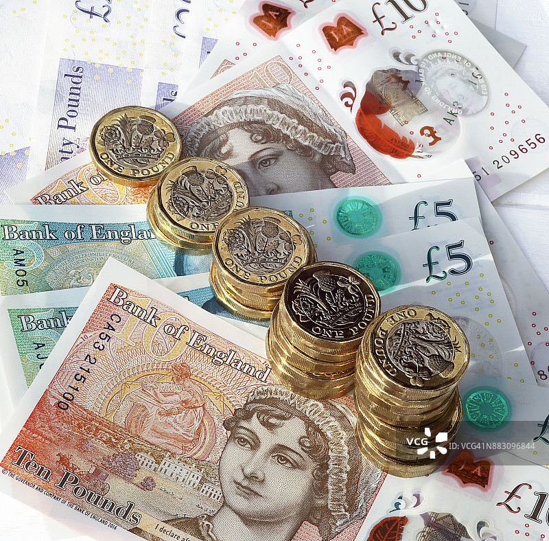 有序堆叠在英镑纸币上的一英镑硬币图片素材