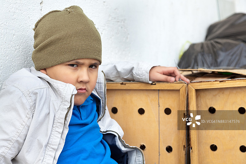 离家出走的少年在一堆物品旁对着镜头怒目而视图片素材