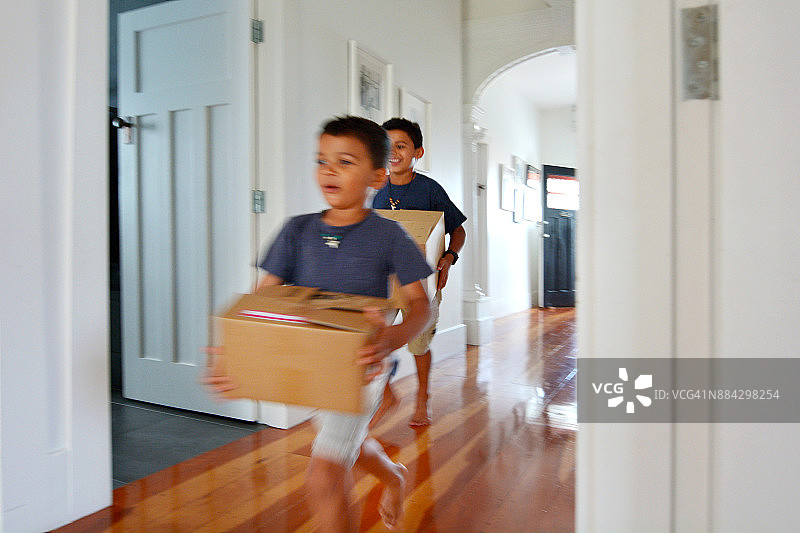 男孩们把搬家箱子搬进新家图片素材