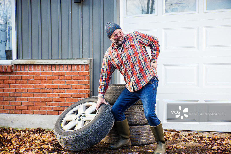 男人费力地举起一个大卡车轮胎图片素材