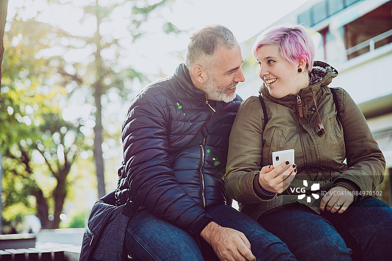 在城市街道上使用手机的年轻女子和中年男人图片素材