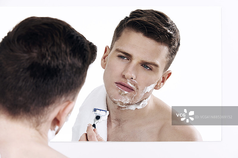 对着镜子刮胡子的男人图片素材