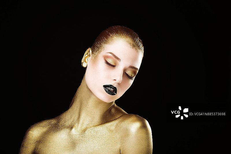 金色人体彩绘，闭着眼睛的年轻女人头部侧面肖像图片素材