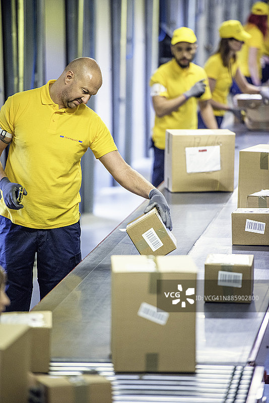 邮政工作人员在传送带上检查包裹图片素材