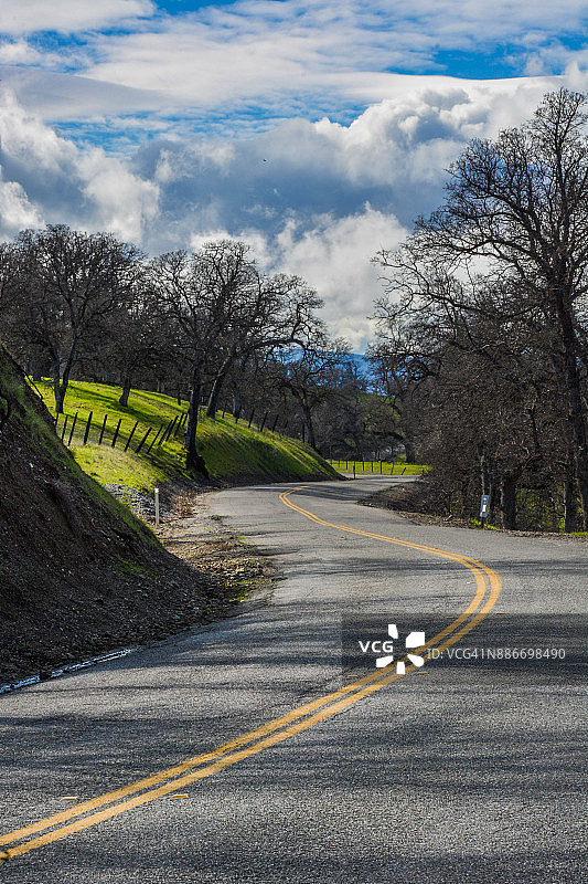 加利福尼亚州格伦县的绿色春天山坡上的蜿蜒乡村公路图片素材