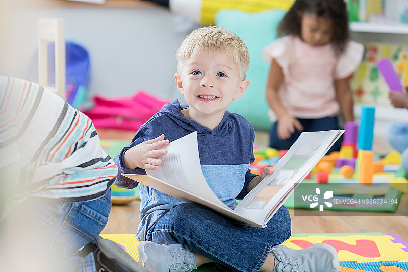 学前班里，小男孩快乐地阅读图画书图片素材