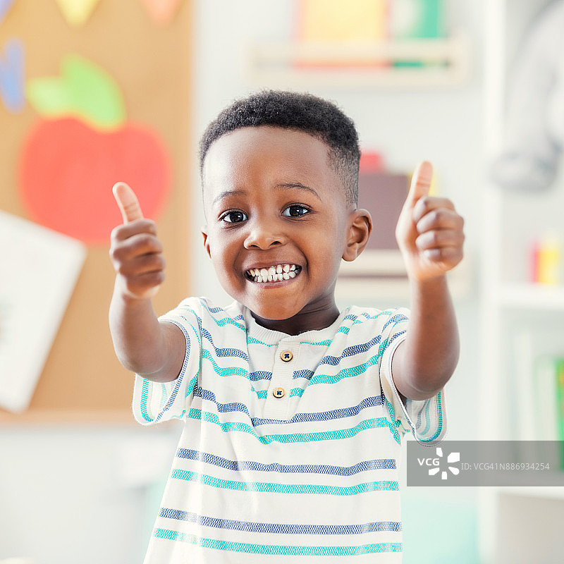 在幼儿园竖起大拇指的可爱男孩的特写图片素材