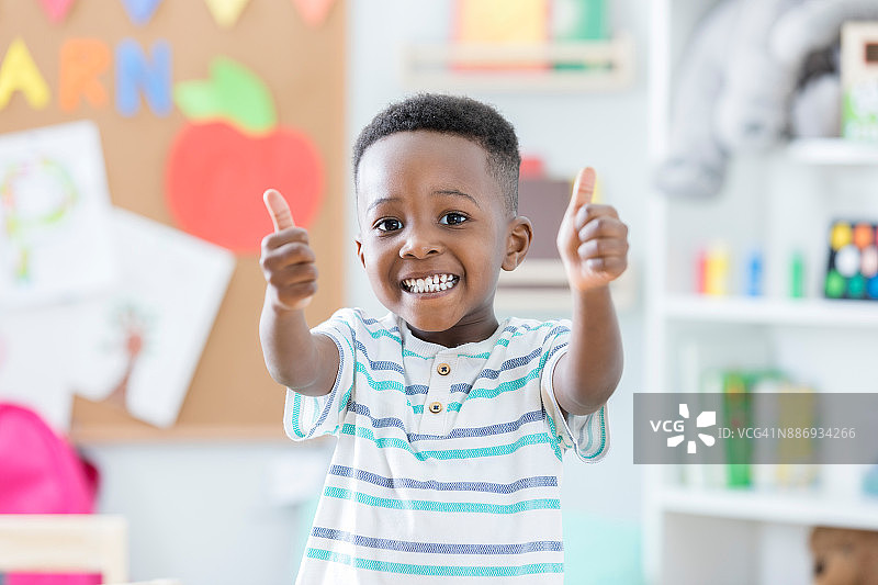 在幼儿园竖起大拇指的可爱男孩图片素材