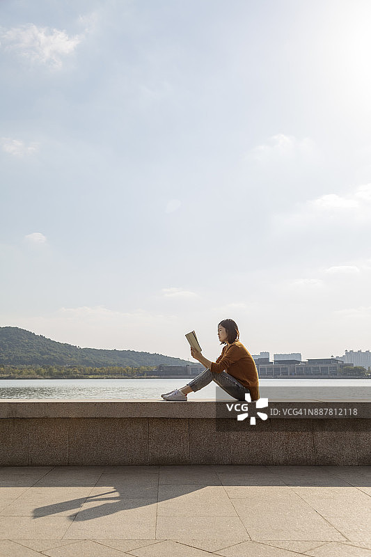 在湖边阅读的年轻亚洲孕妇图片素材