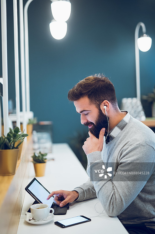 在咖啡吧使用平板电脑的年轻男人图片素材