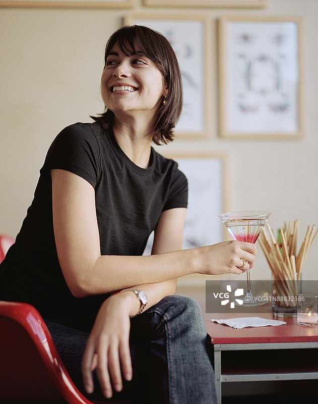 拿着马提尼酒坐在桌旁的女人图片素材