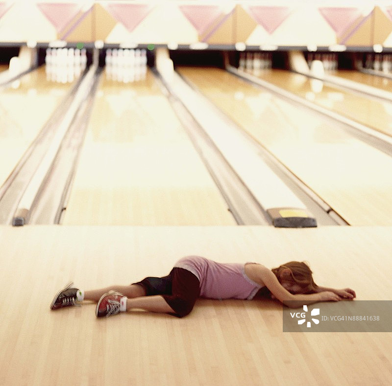 女孩躺在保龄球馆里图片素材