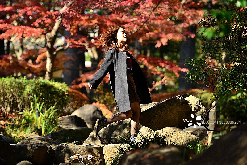 走在东京小溪踏脚石上的年轻日本女子图片素材