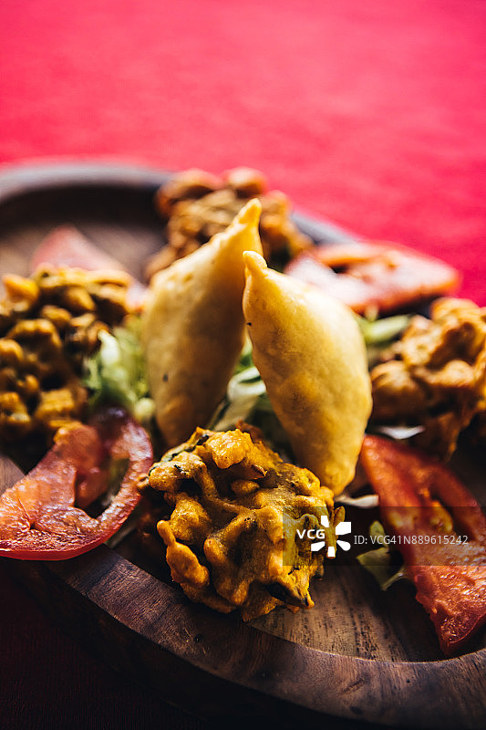 木盘上的印度炸蔬菜、蔬菜饼和萨摩萨三角饺。北印度食物图片素材
