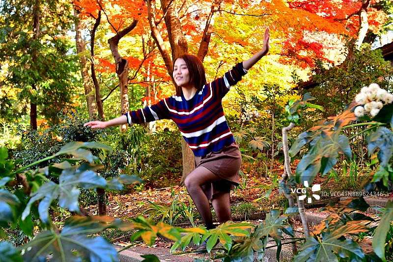 在东京井之头公园美丽的秋叶下的年轻日本女人图片素材