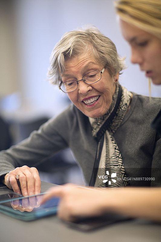 年轻女人帮助老年人使用科技设备图片素材