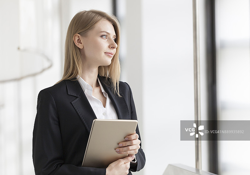 快乐的年轻女商人拿着平板电脑站立图片素材