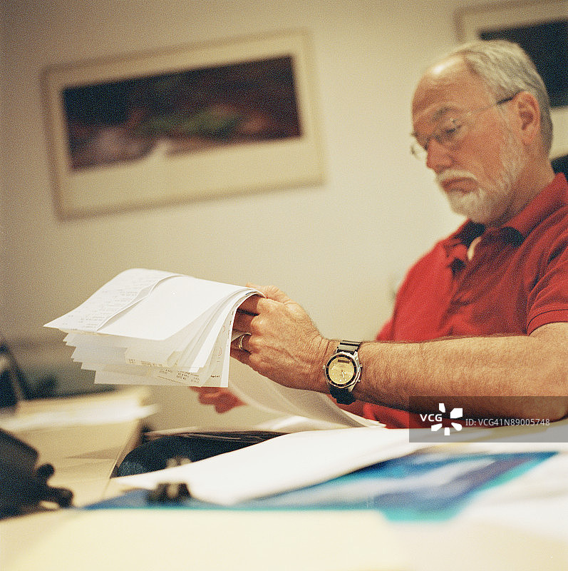 男子坐在办公桌旁处理文件图片素材