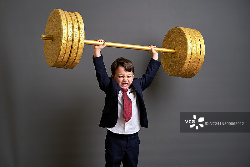 举起金色杠铃的可爱商务男孩图片素材