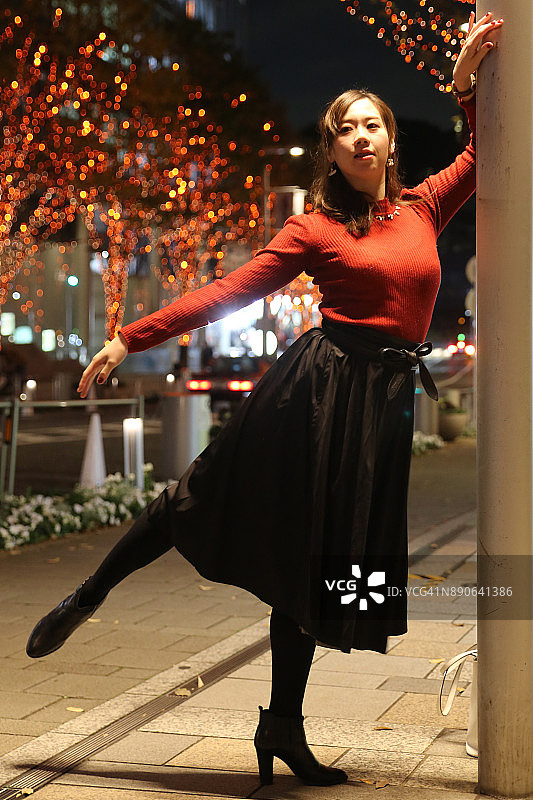在圣诞灯饰下跳舞的年轻女人图片素材