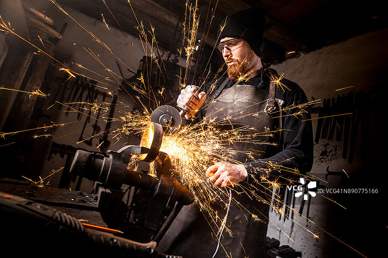 铁匠用角磨机切割废铁，火花四溅图片素材