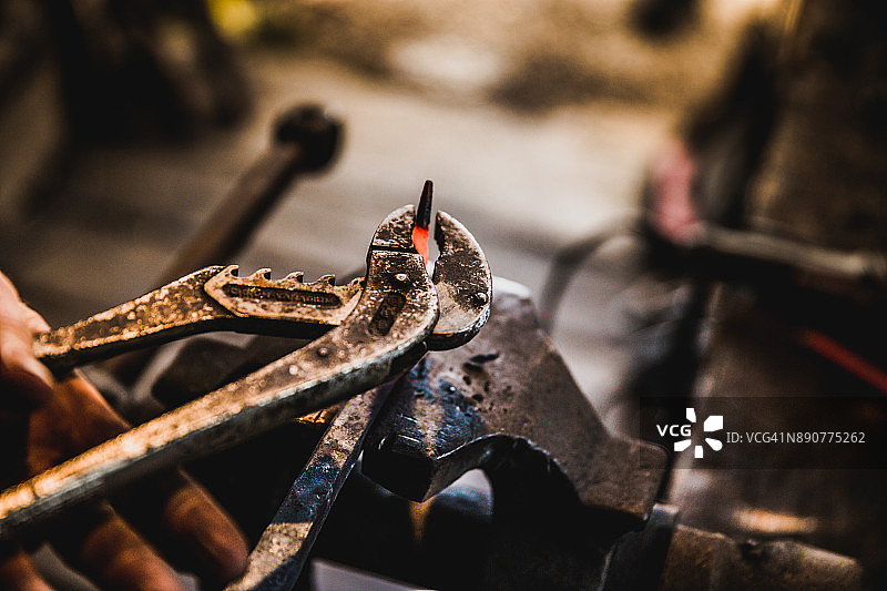 用锁钳塑造一块熔铁图片素材